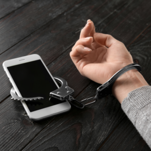 Person in handcuffs holding a smartphone, representing online speech criminalization